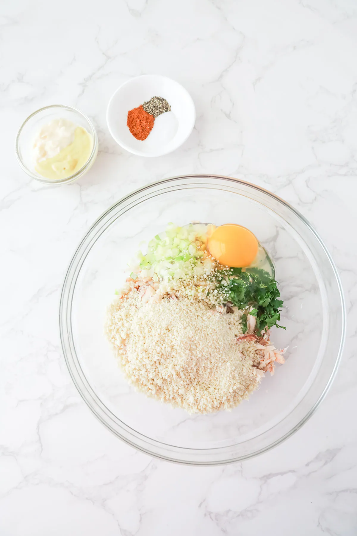 Crab meat, breadcrumbs, egg, parsley, and green onion in a mixing bowl.