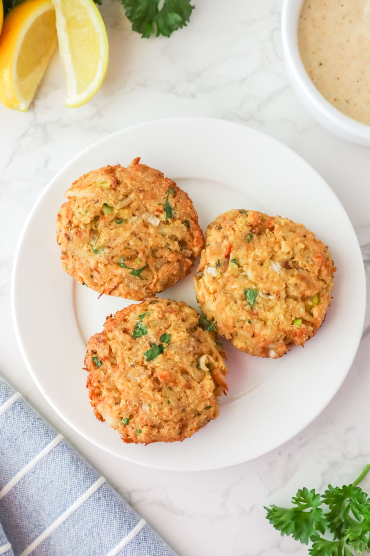 Three crab cakes served on a white plate.