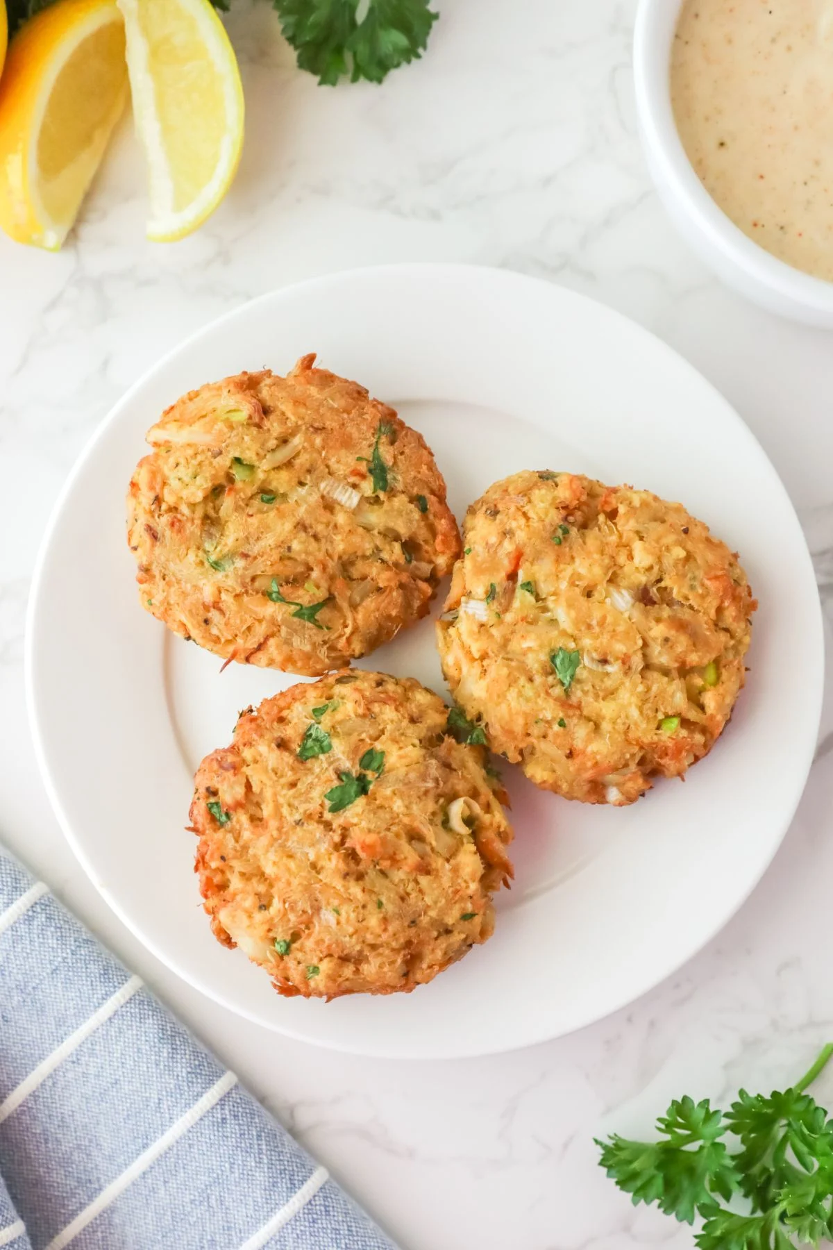 Three crab cakes served on a white plate.