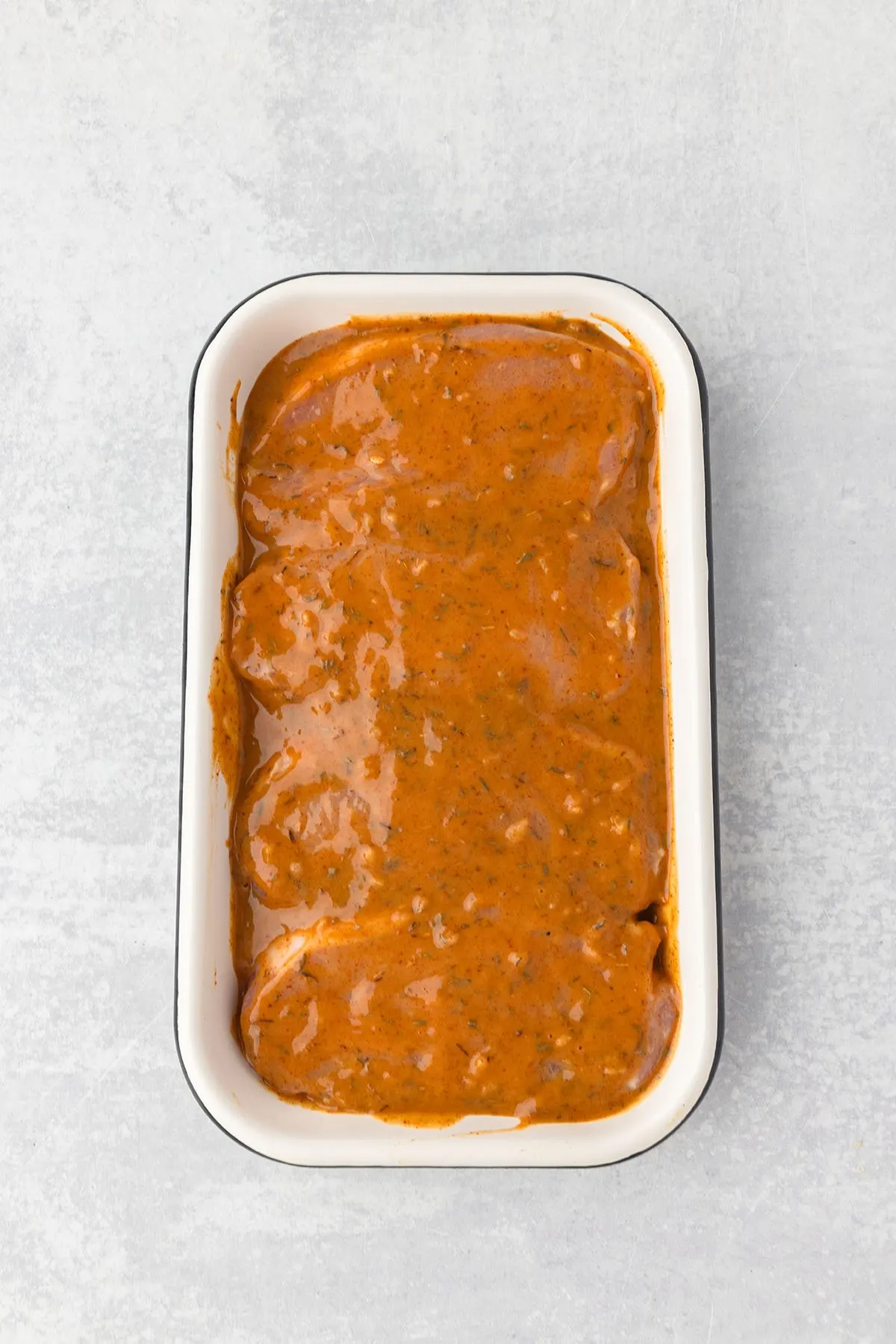 Pork chops covered in
honey mustard marinade in a shallow container.