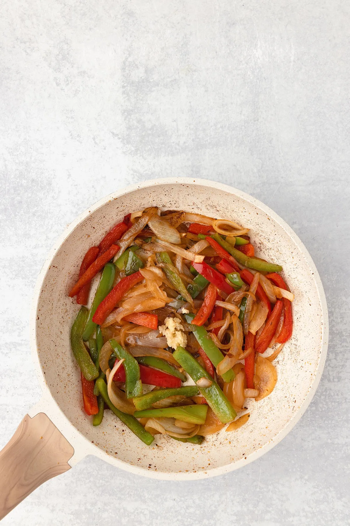 Sauteed onions, green and red peppers with garlic in a skillet.