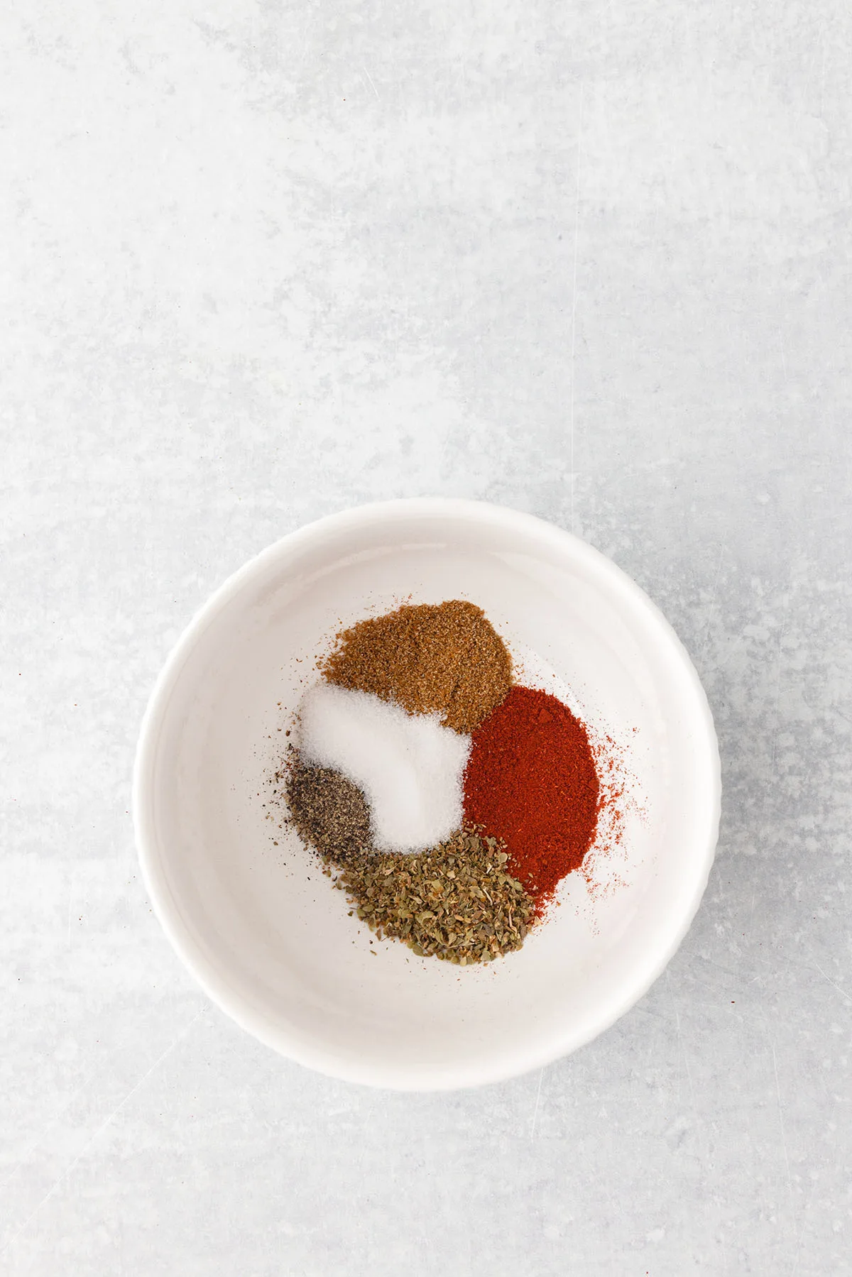 Smoked paprika, salt, cumin, dried oregano and black pepper in a small bowl.