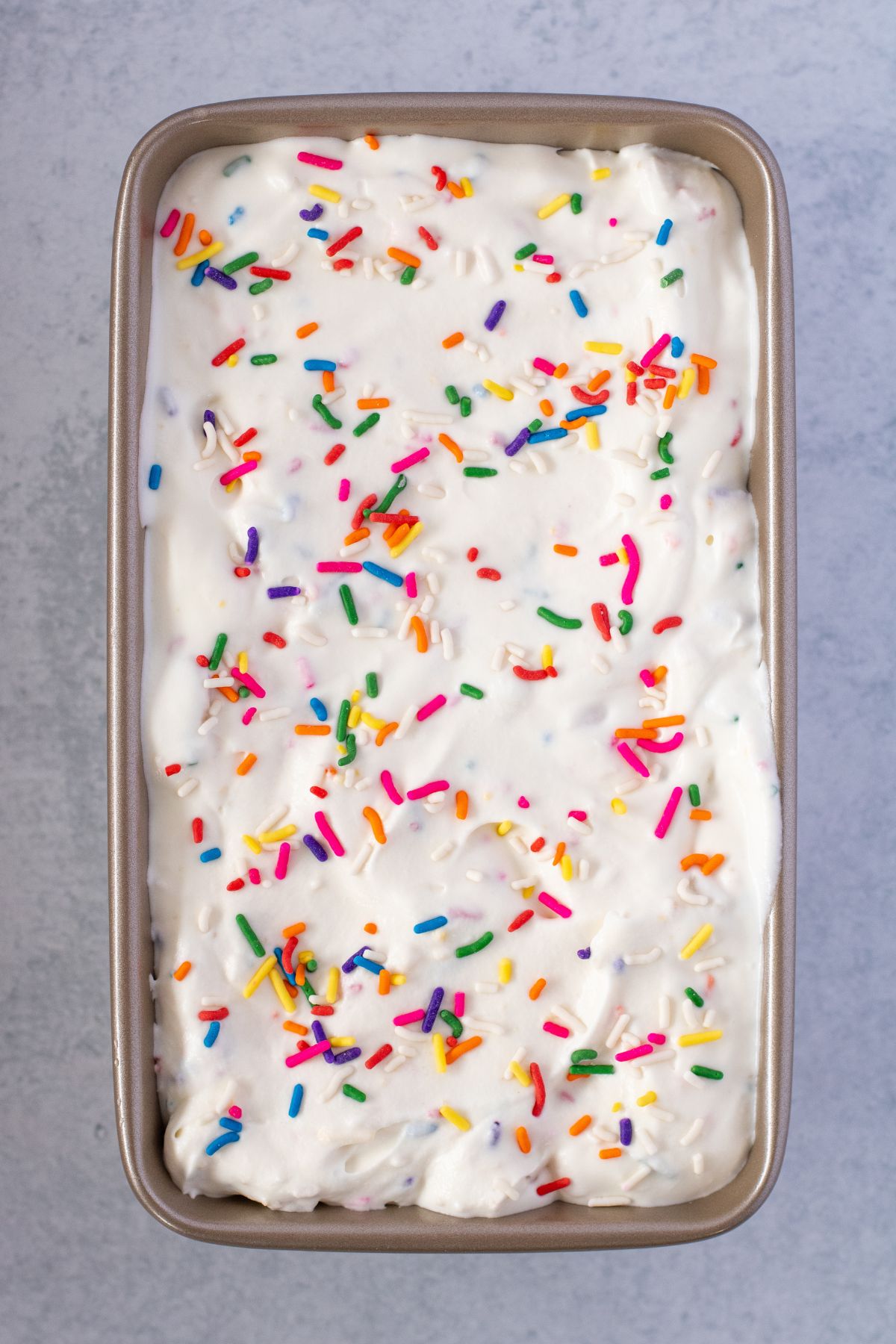 Golden Oreo Ice cream in a metal loaf pan topped with sprinkles.