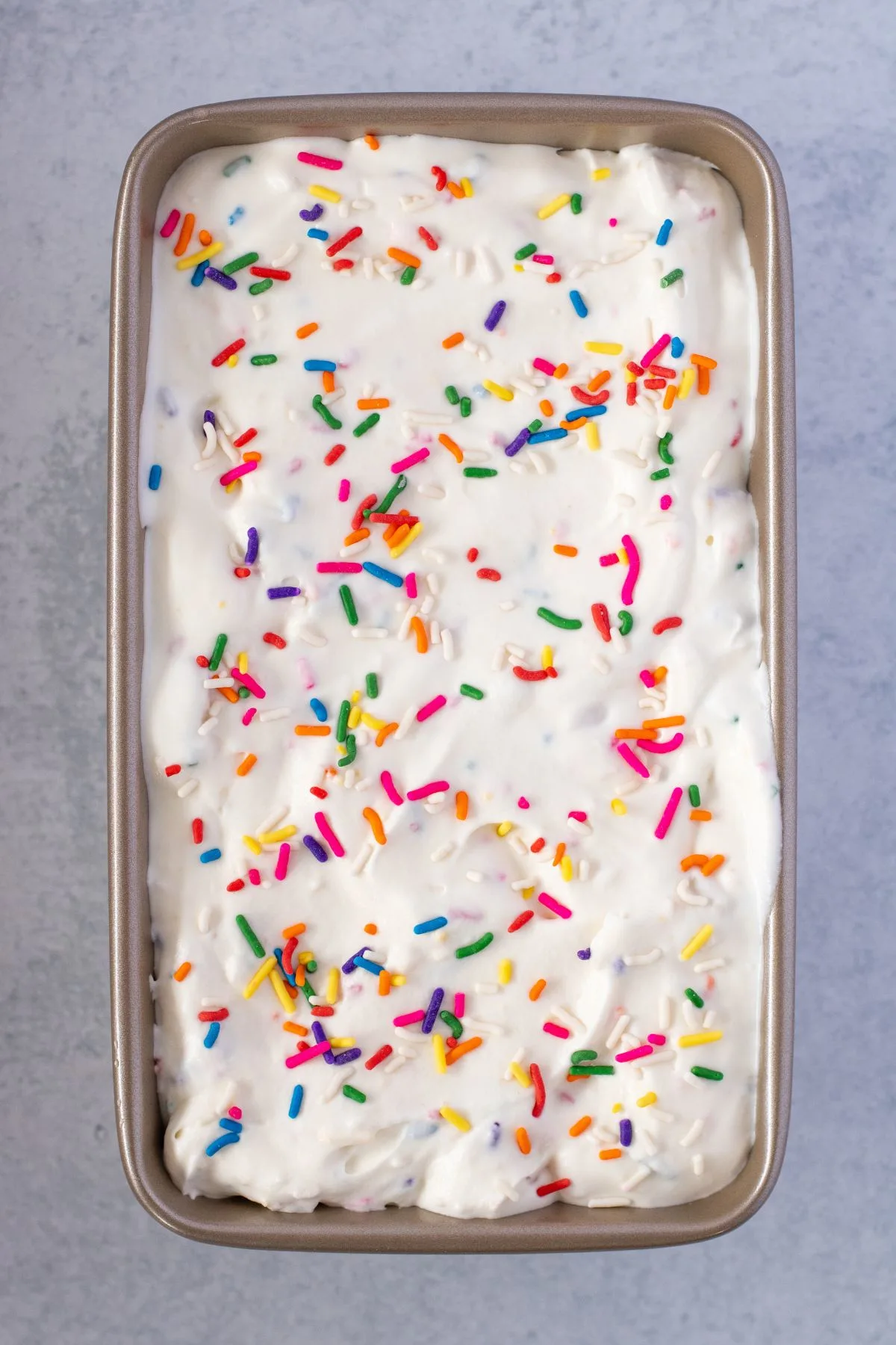 Golden Oreo Ice cream in a metal loaf pan topped with sprinkles.