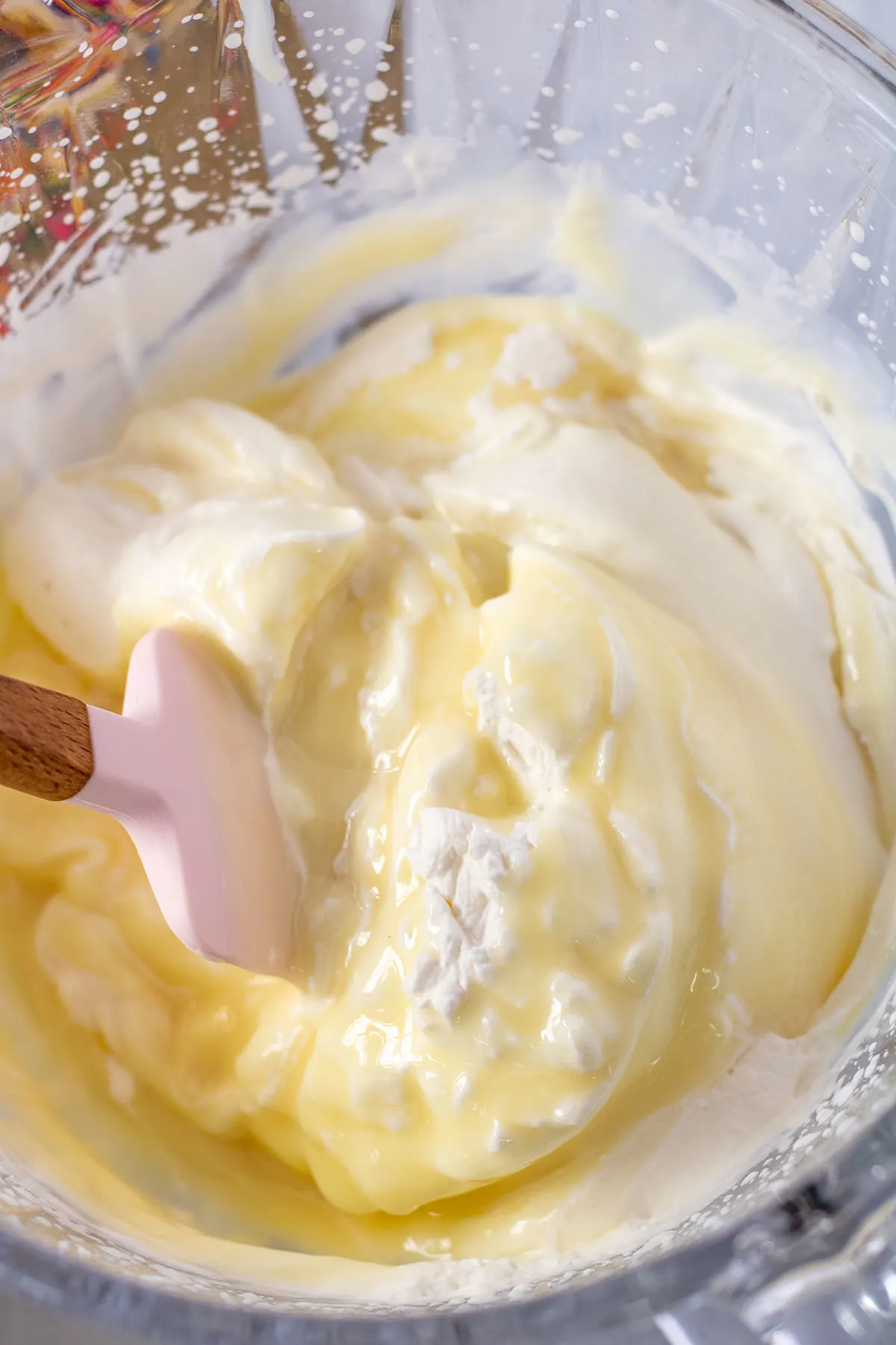 Sweetened condensed milk folded into whipped cream in the mixing bowl.