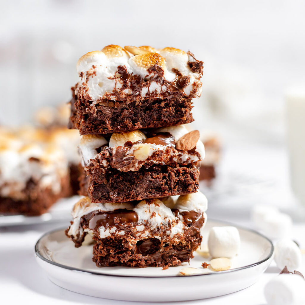 Three rocky road brownies stacked on a white plate.