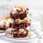 Three rocky road brownies stacked on a white plate.