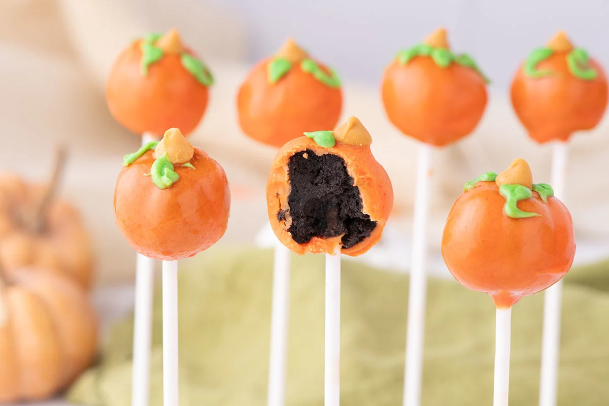 Pumpkin Cake Pops on a stick with a bite taken out of one.