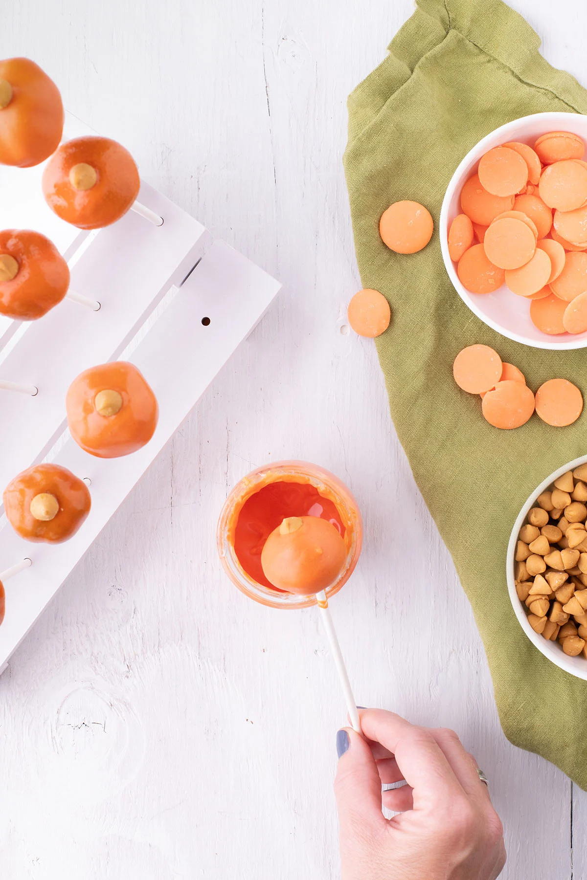 Dipping cake pops into melted orange candy and topping with a butterscotch chip.