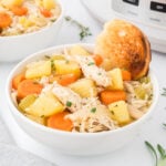 A serving of chicken stew in a white bowl with toasted bread.