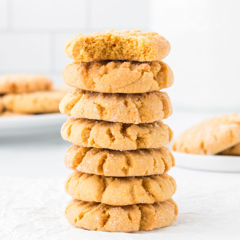 Seven peanut butter cookies stacked on parchment paper.