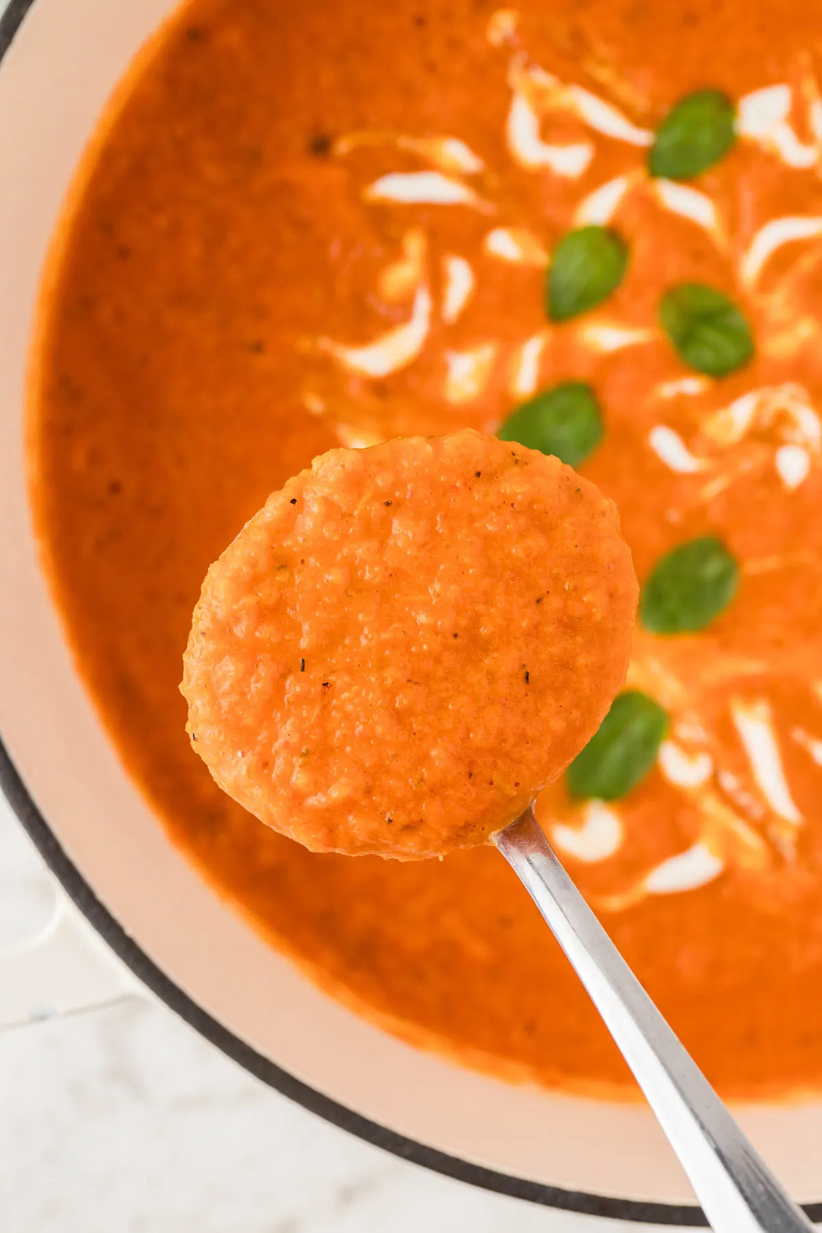Roasted Red Pepper Soup in a large pot with a serving in a large spoon.