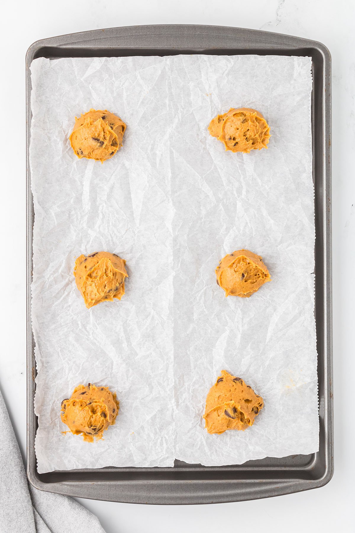 Spice cake pumpkin cookie dough on a parchment-lined baking sheet.