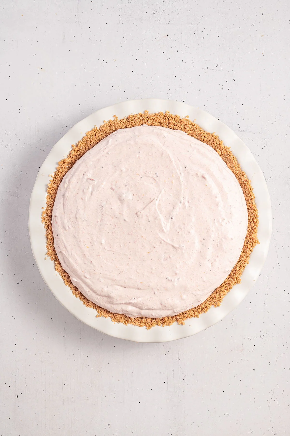 Cranberry Cream cheese filling poured into graham cracker crust in the pie dish.