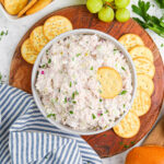 Ham Salad in a bowl served on round wooden board with crackers and grapes.