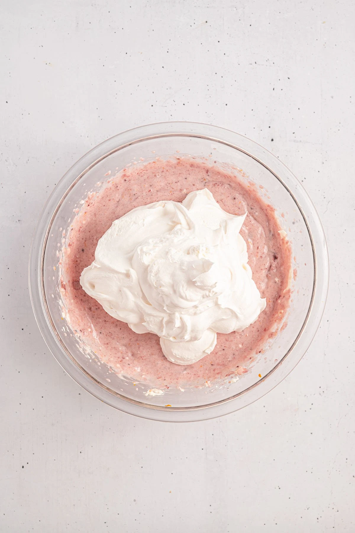 Whipped topping added to the cranberry cream cheese mixture in the glass mixing bowl.