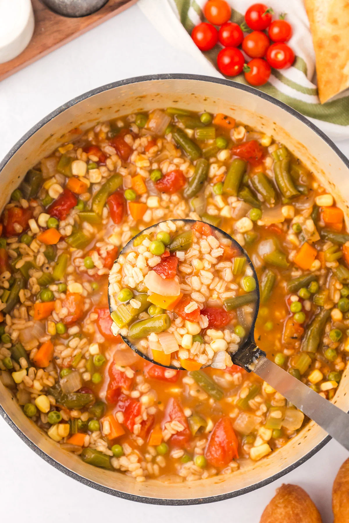 Vegetable barley soup in a large pot with a serving in a spoon.