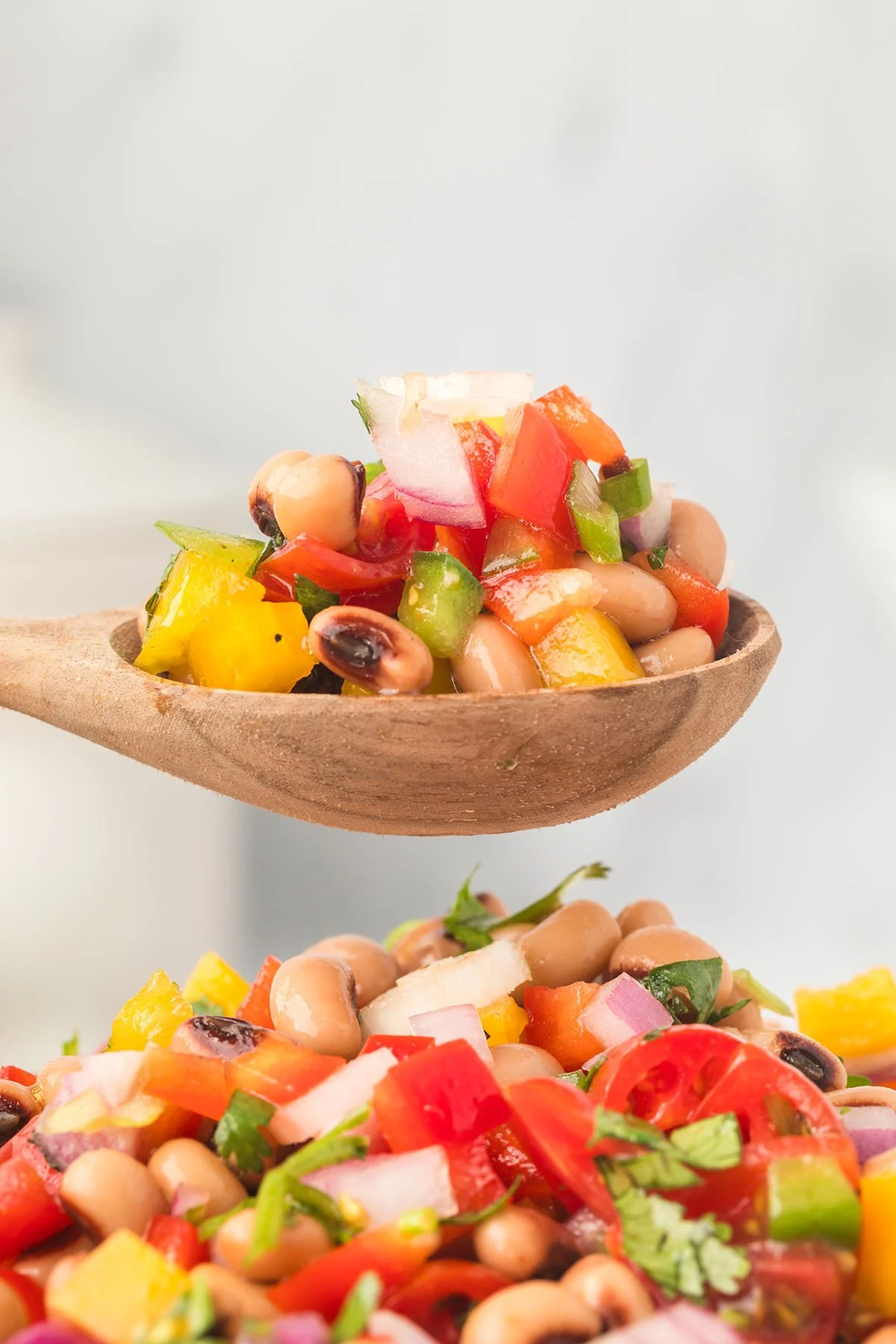 A serving of Black Eyed Pea Salad in a wooden spoon.