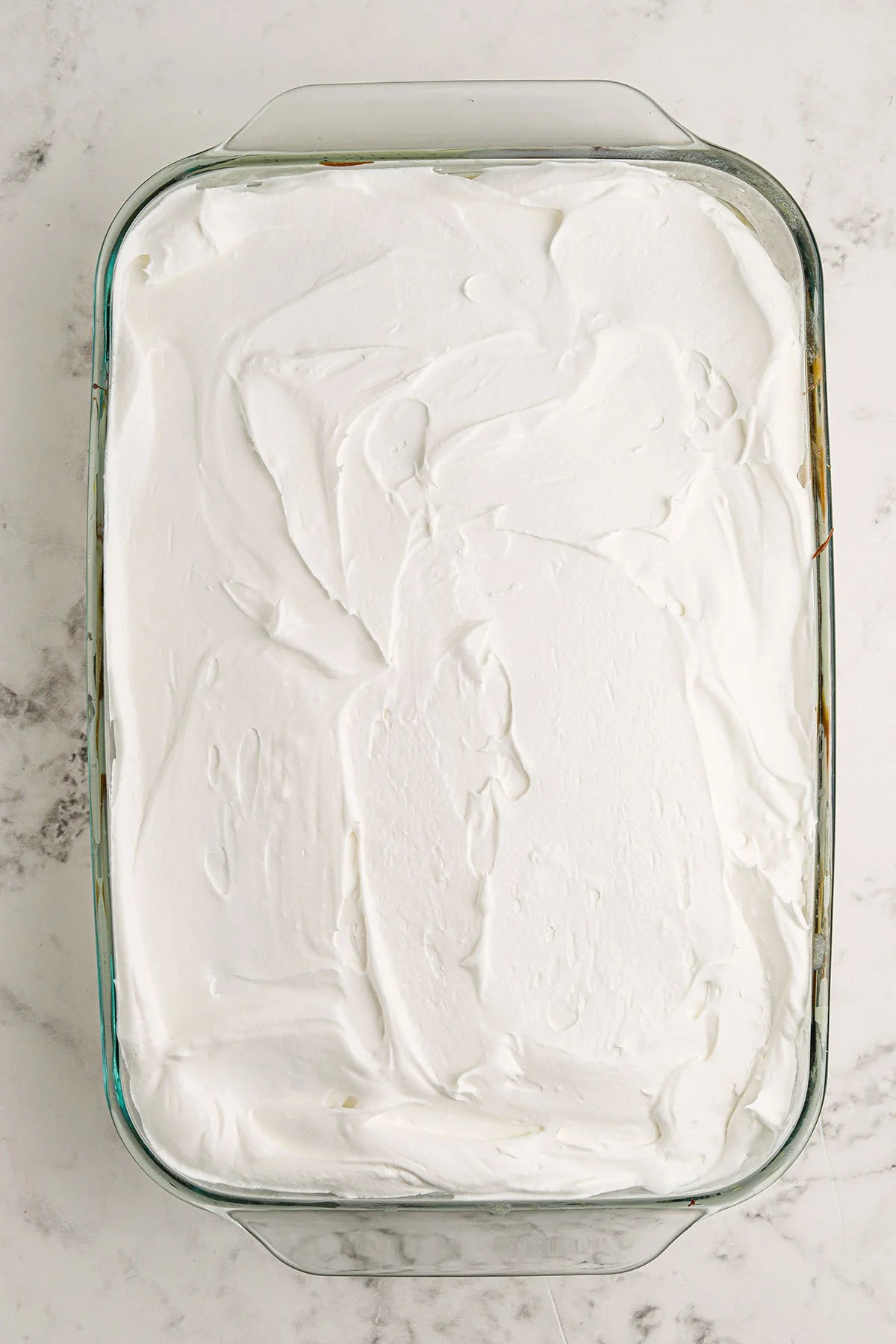 Cool Whip spread over the top of the chocolate cake in glass baking dish.