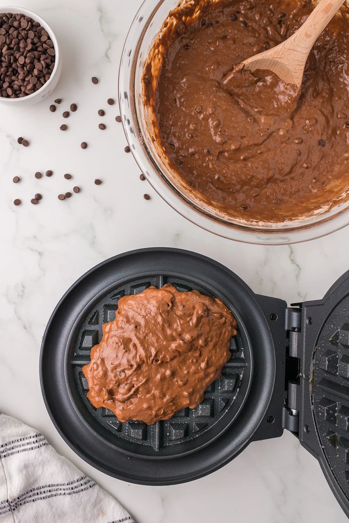 Chocolate waffle batter is poured into a waffle maker.
