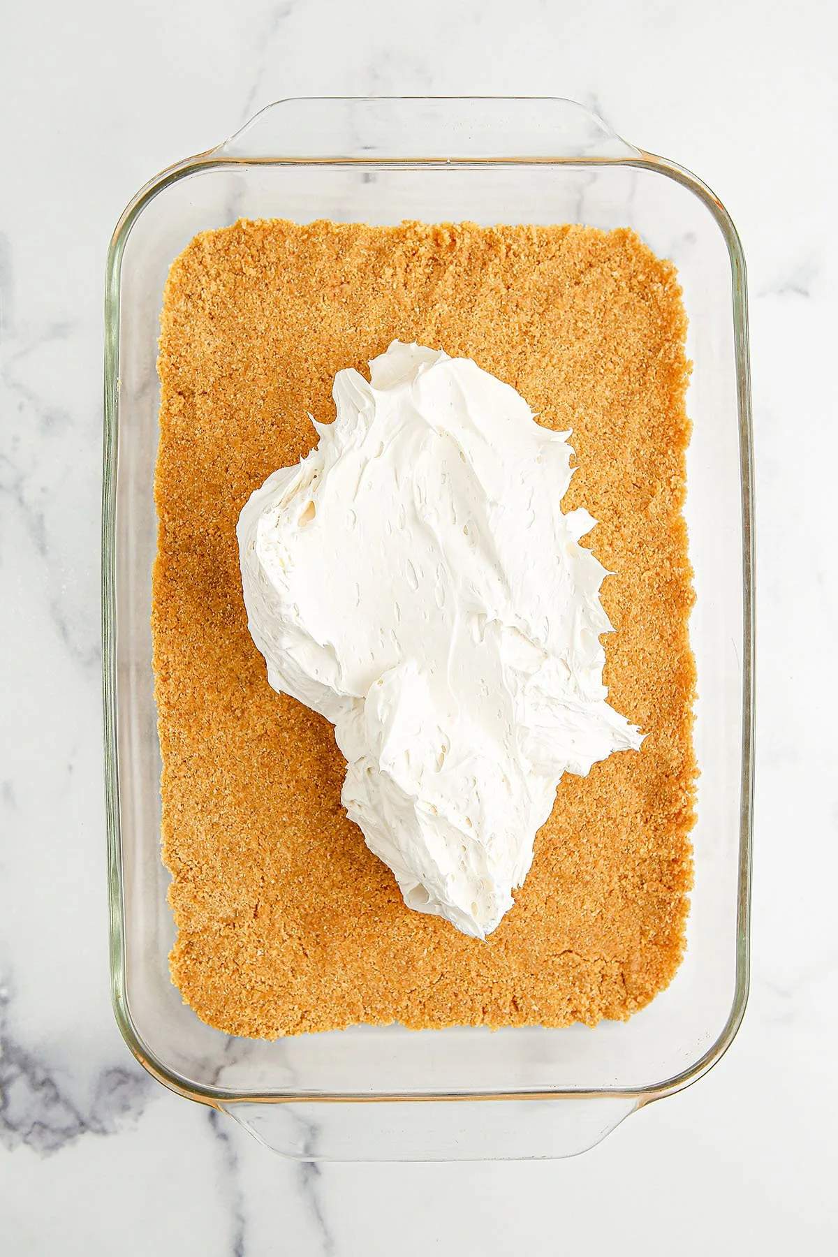 Cream cheese mixture spread over graham cracker crust in the glass baking dish.