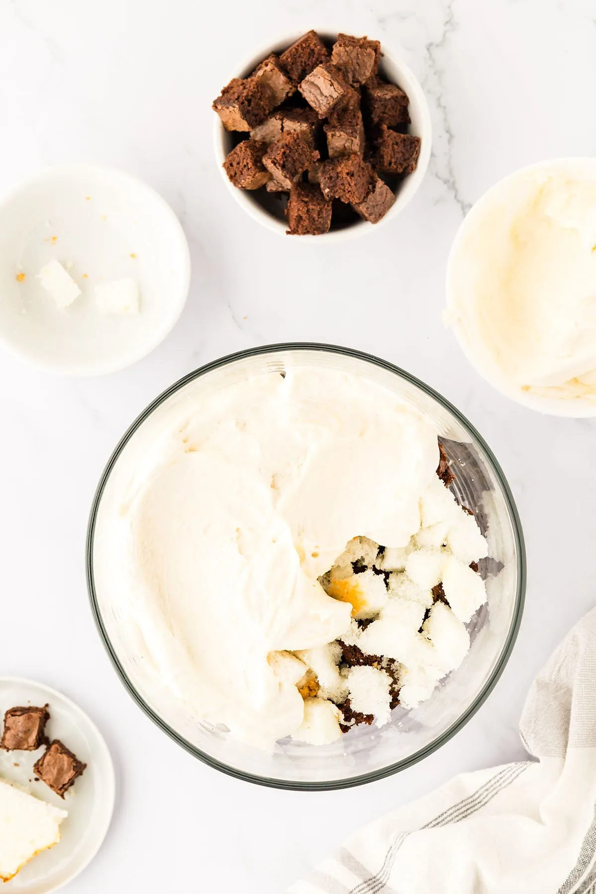 A layer of white chocolate pudding poured over cubed brownies and angel food cake in the glass trifle bowl.