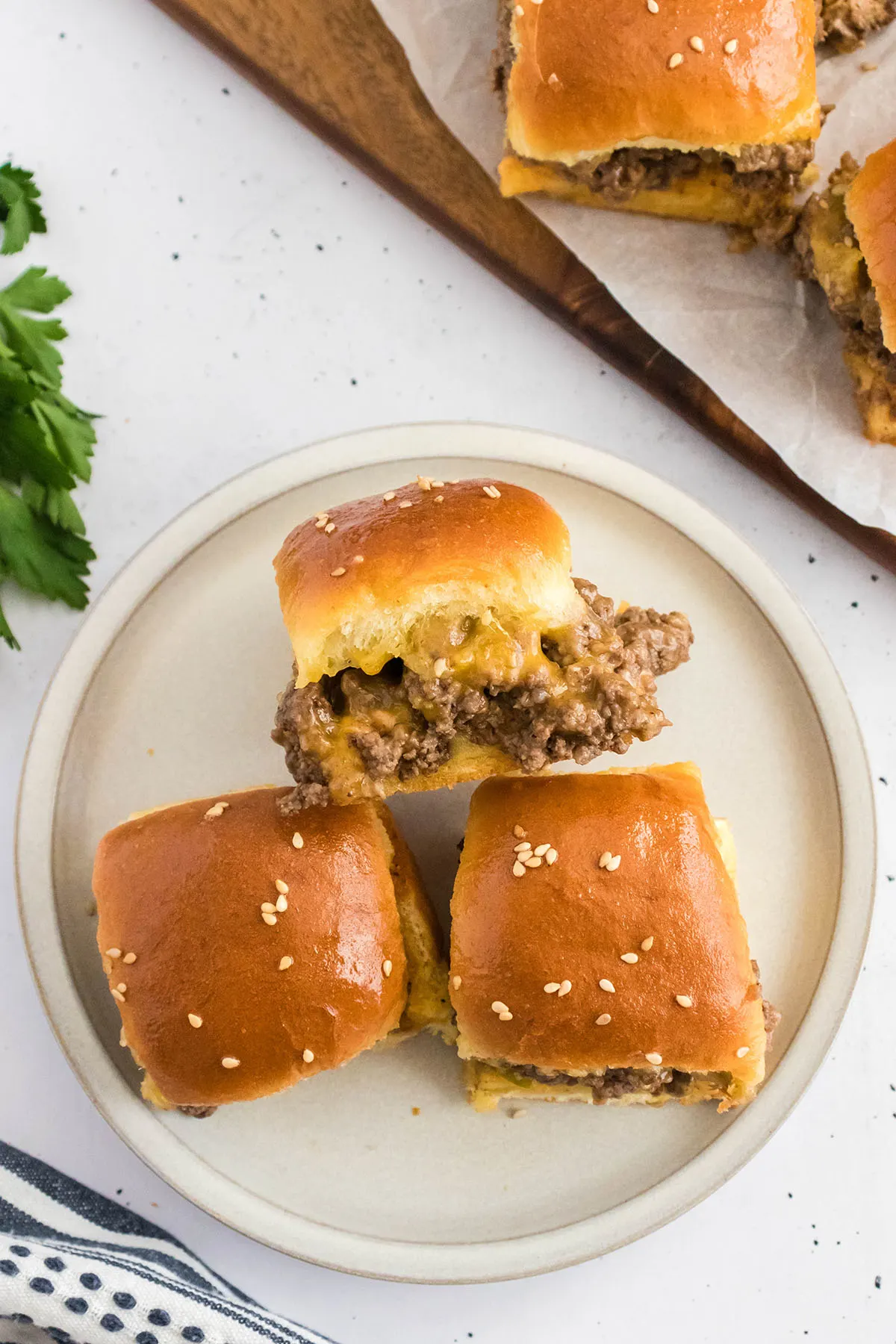Three Cheeseburger Sliders on a round white plate.