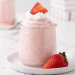 Strawberry Mousse served in a dessert glass topped with cool whip and a sliced strawberry.