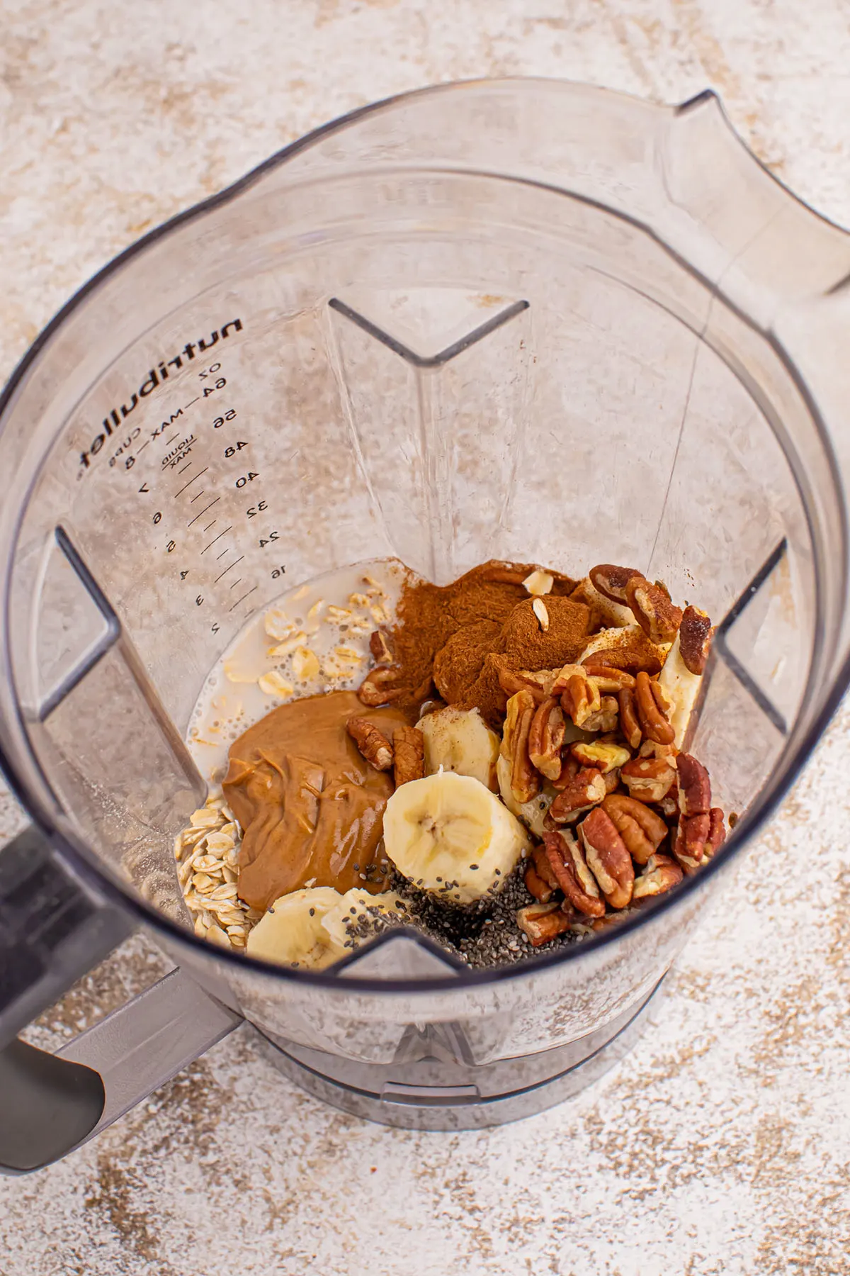 Frozen banana, milk, oats, nuts, nut butter, maple syrup, chia seeds, cinnamon, and vanilla added to the blender.