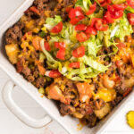Big Mac Casserole topped with shredded lettuce and sliced tomatoes in a baking dish.