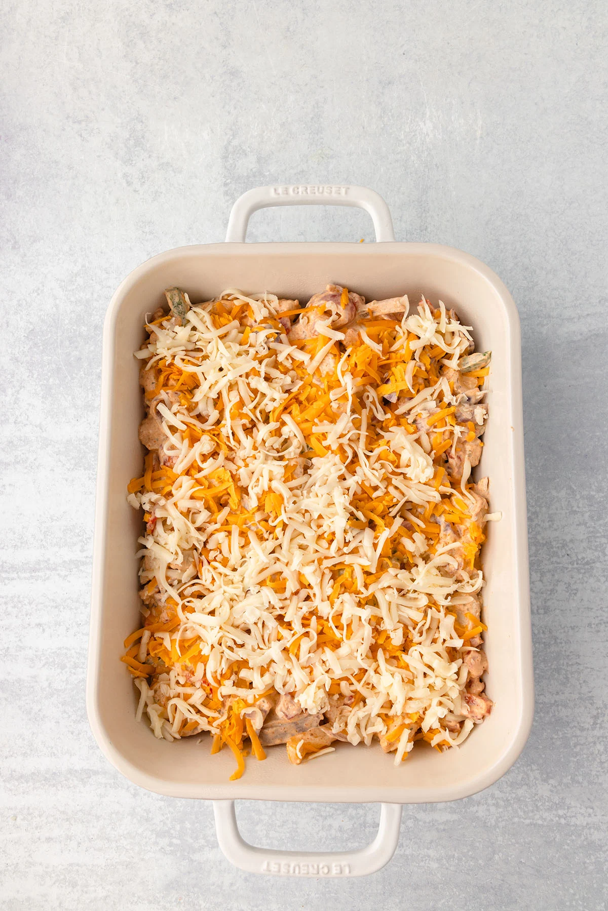 Chicken Fajita Casserole filling topped with shredded cheese in the baking dish.