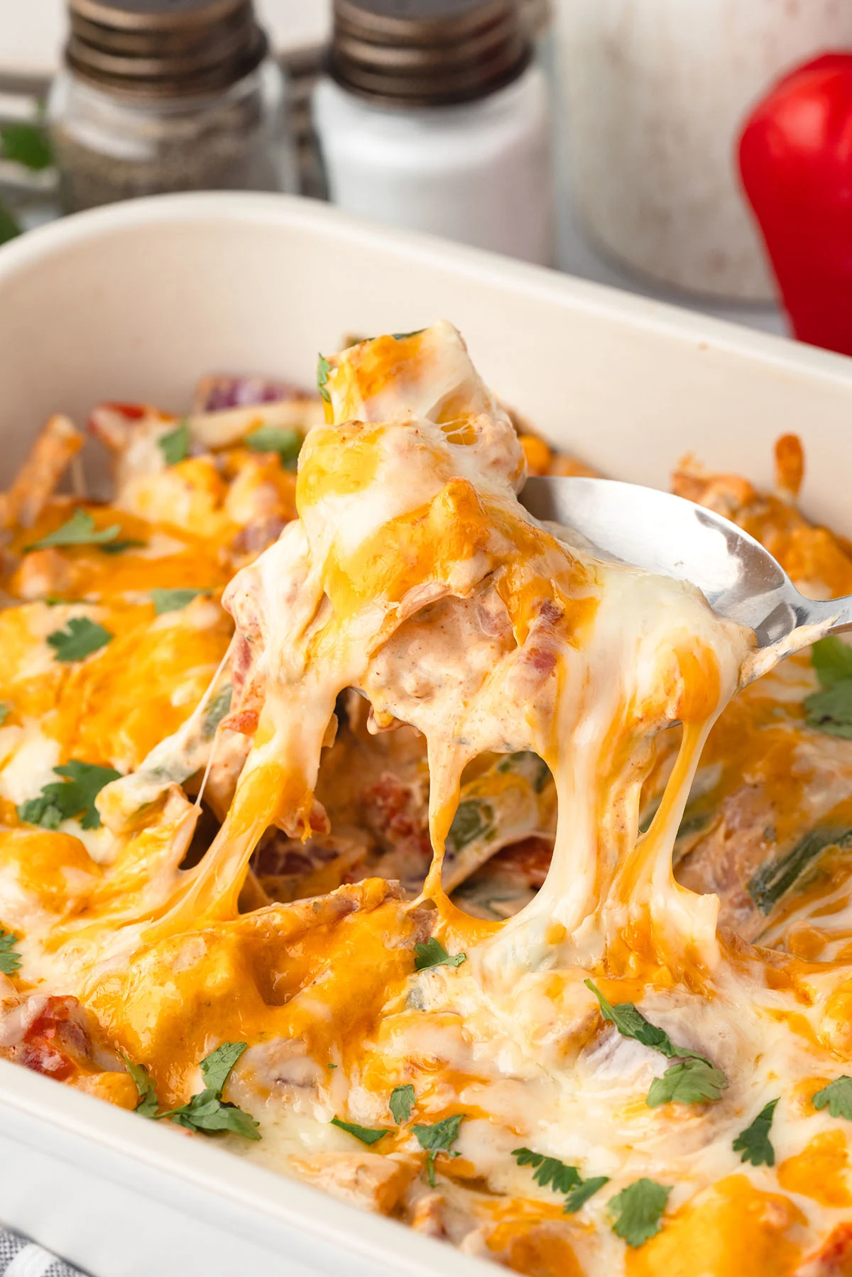 Chicken Fajita Casserole in a baking dish, served with a spoon.