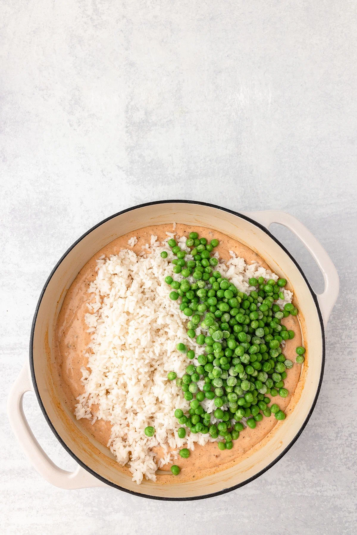 Rice and green peas are added to the cream of chicken mixture in the skillet.