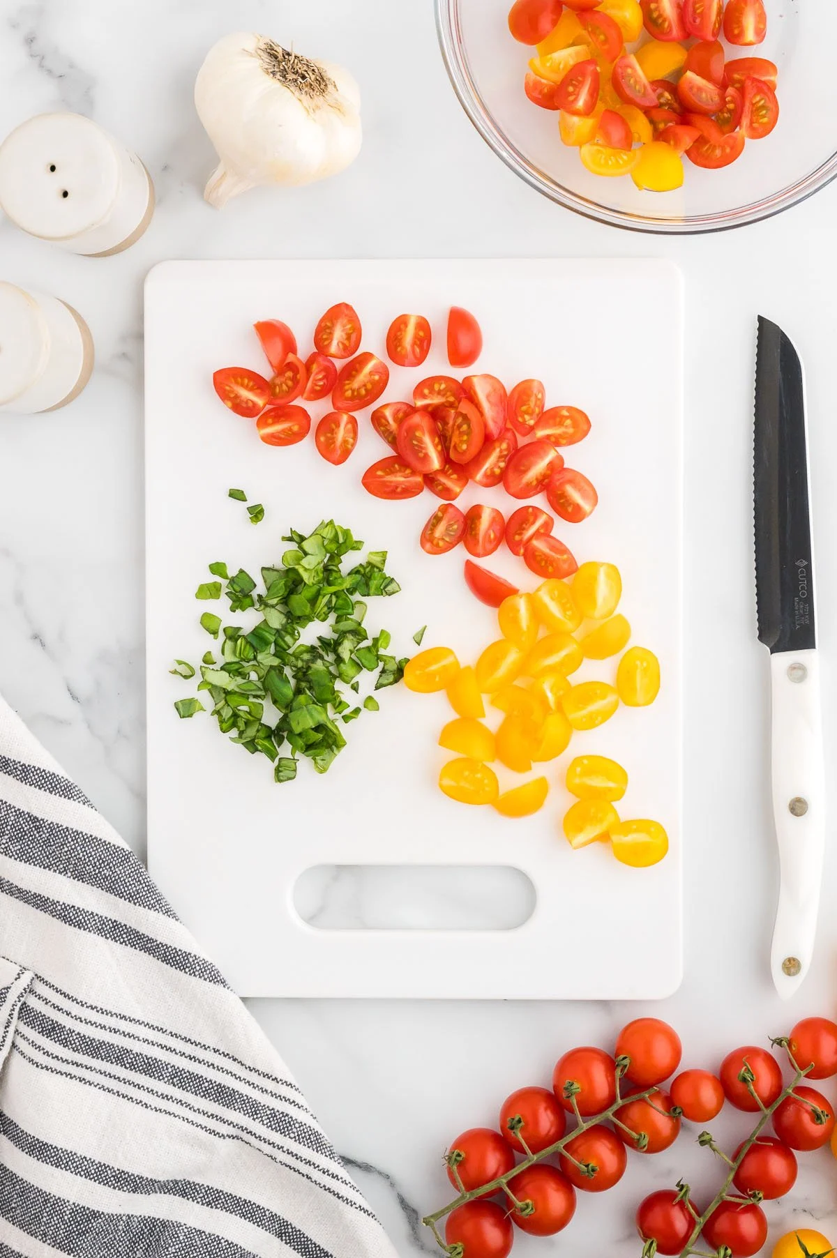 Cherry tomatoes and basil on a cutting board.