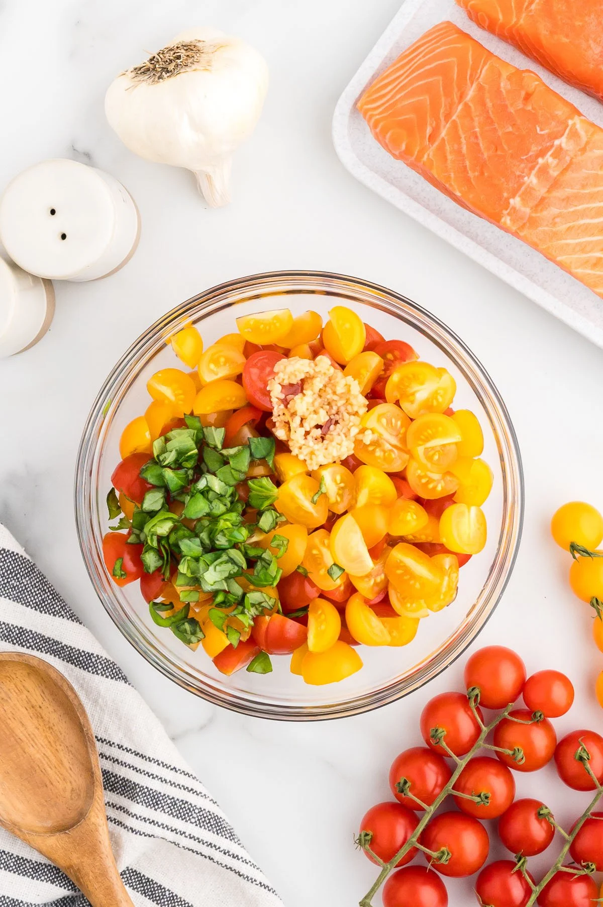 Cherry tomatoes, basil, and minced garlic in a mixing bowl.