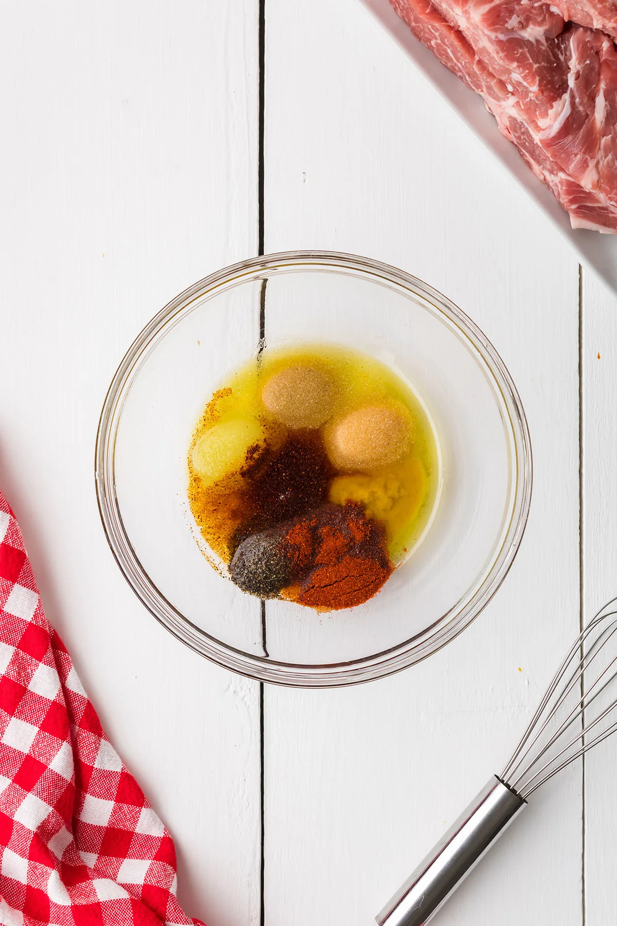 Olive oil and spices in a glass mixing bowl.