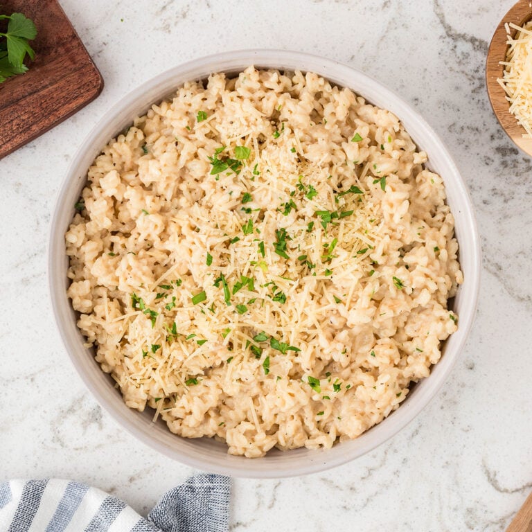 Parmesan Risotto served in a white bowl, topped with chopped parsley.