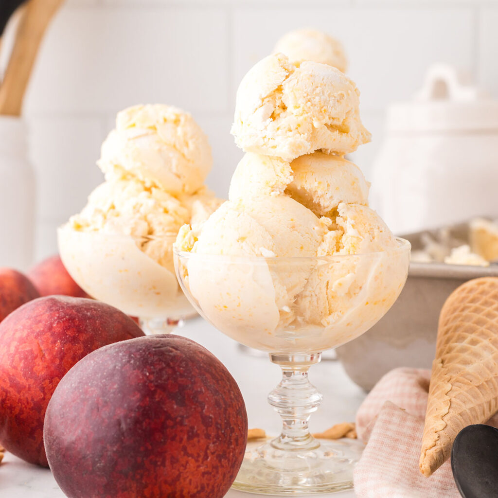 Scoops of Peach Ice Cream are served in dessert glass bowls.
