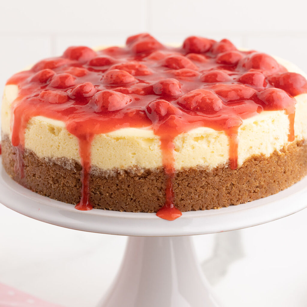 Strawberry cheesecake on a white cake stand.