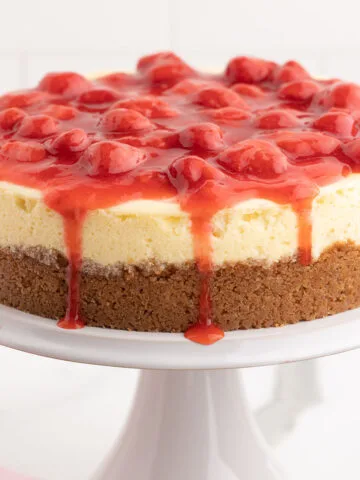 Strawberry cheesecake on a white cake stand.