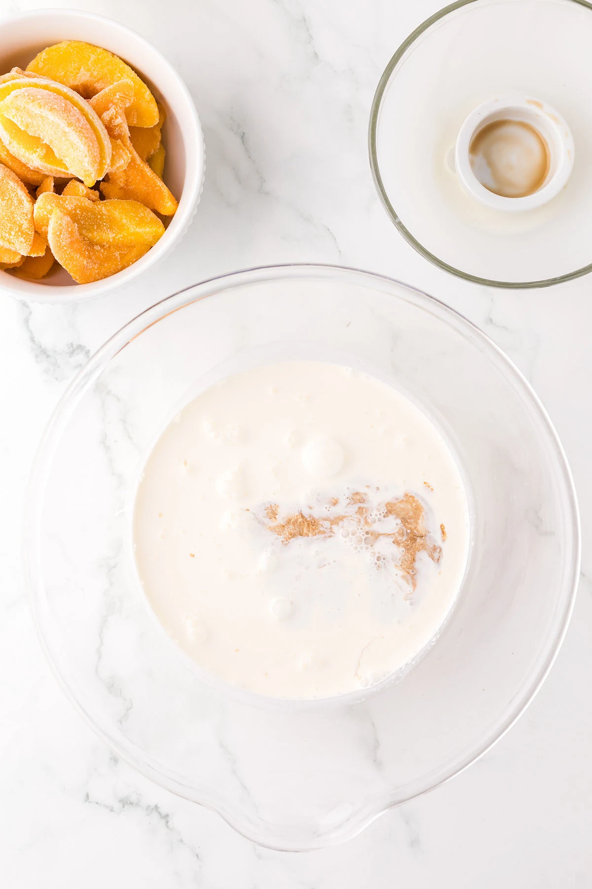 Heavy cream and vanilla in a glass mixing bowl.