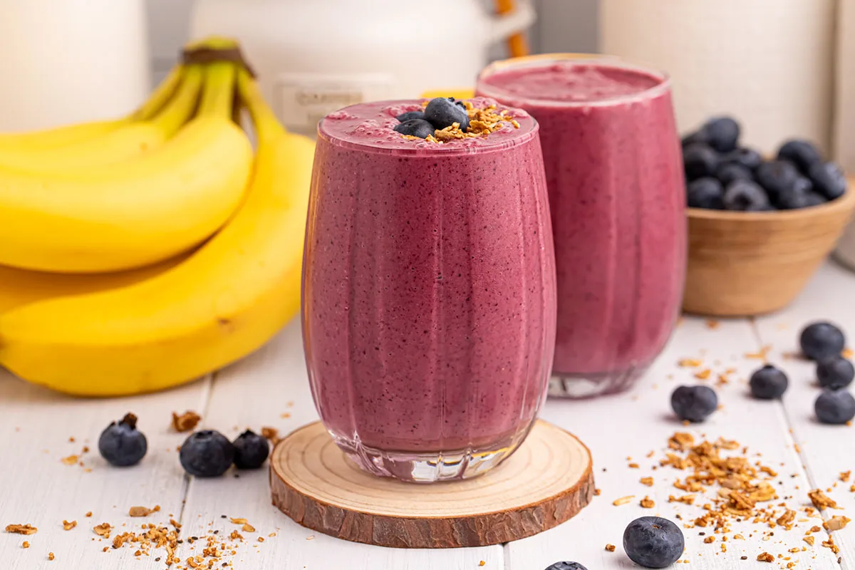 Blueberry Mango Smoothies in two glasses, topped with blueberries and granola.