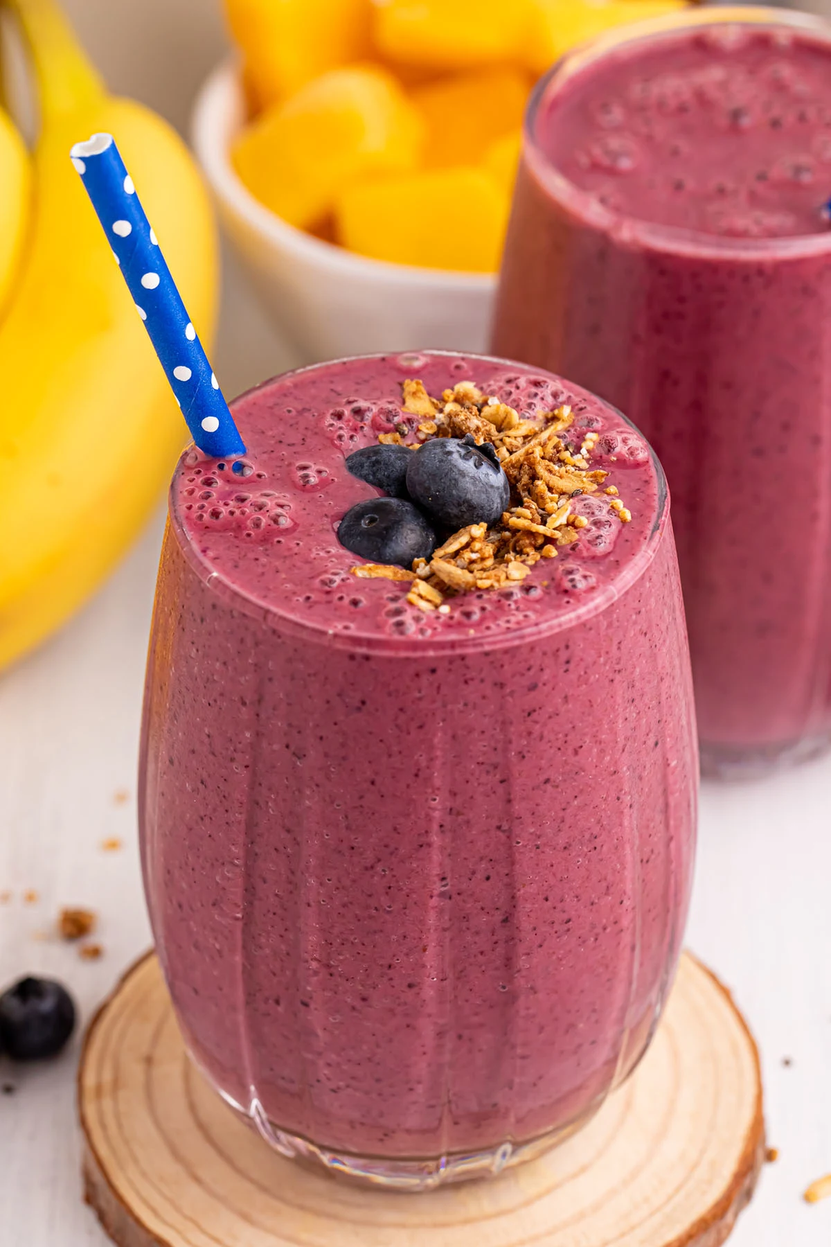 Blueberry Mango Smoothie served in a glass topped with blueberries and a sprinkle of granola.