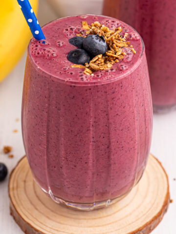 Blueberry Mango Smoothie served in a glass topped with blueberries and granola.