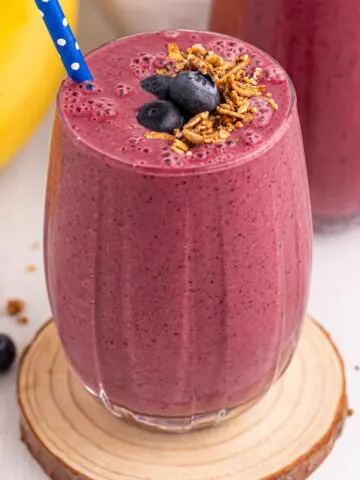 Blueberry Mango Smoothie served in a glass topped with blueberries and granola.