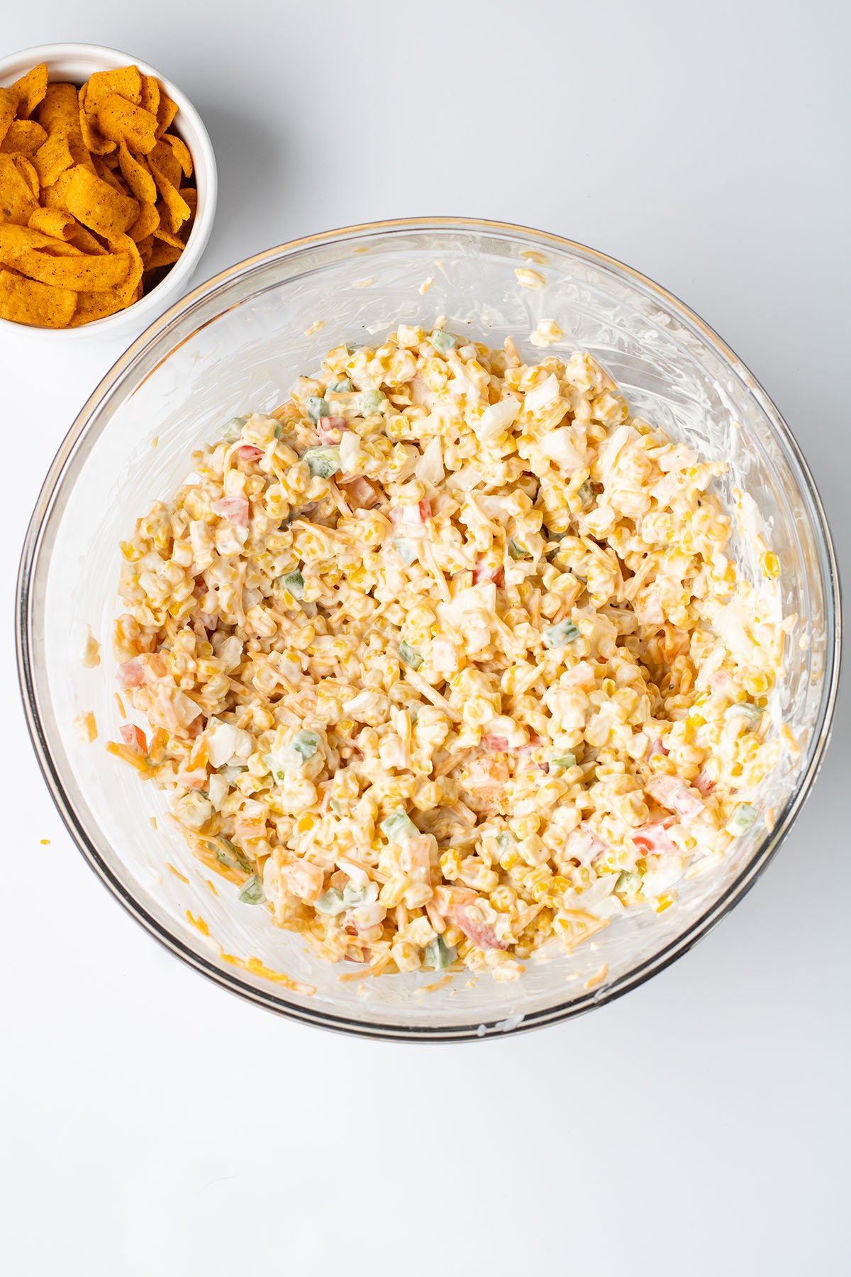 Frito corn salad mixed together in a glass mixing bowl.