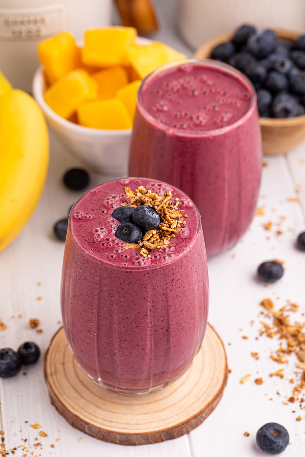 Blueberry Mango Smoothie served in two glasses, with one topped with blueberries and granola.