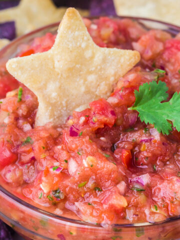 Salsa in a clear bowl topped with a star chip.