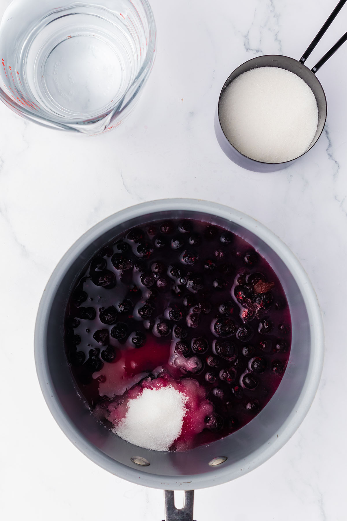 Blueberries, sugar, and water in a saucepan.