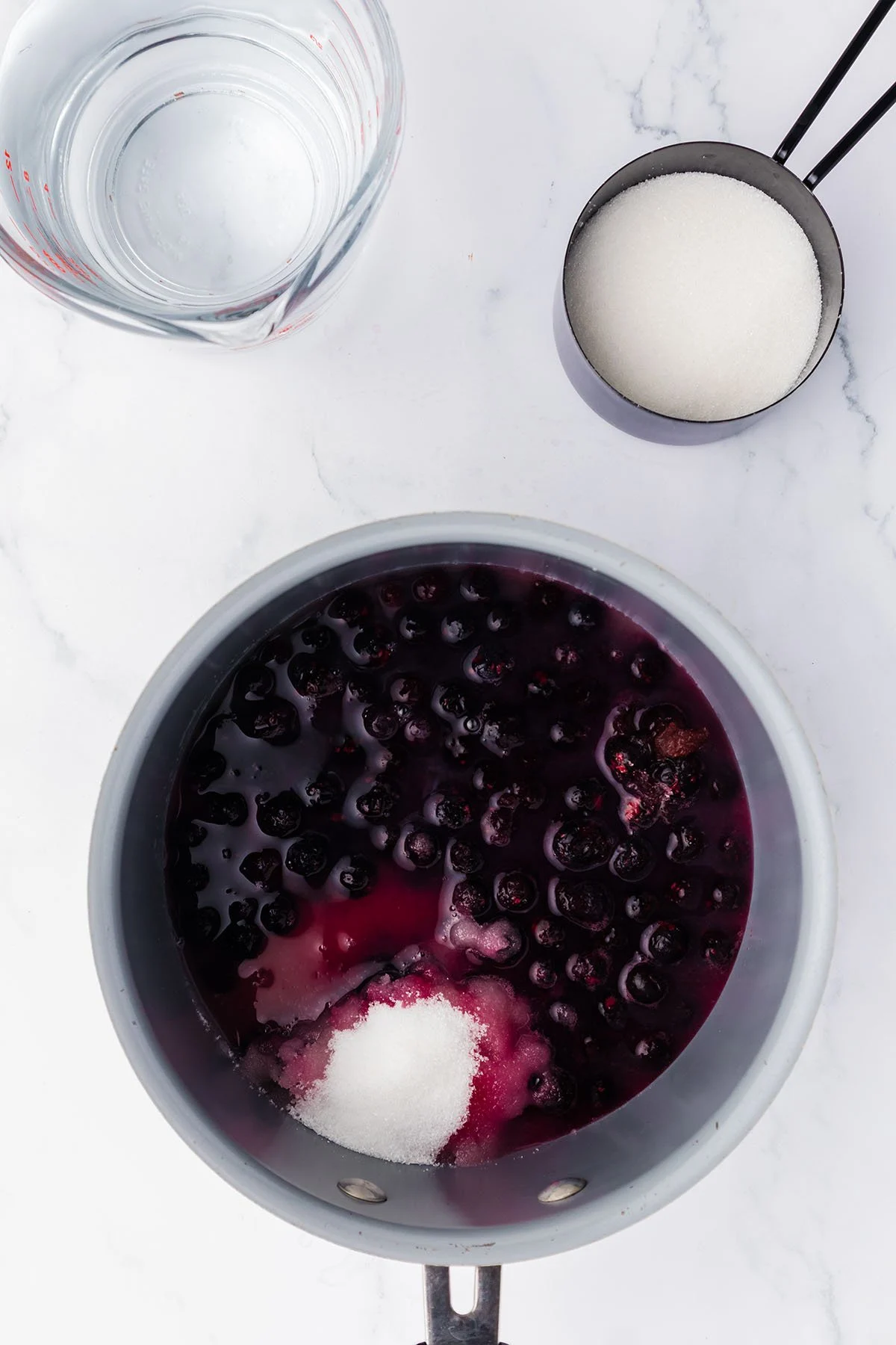 Blueberries, sugar, and water in a saucepan.